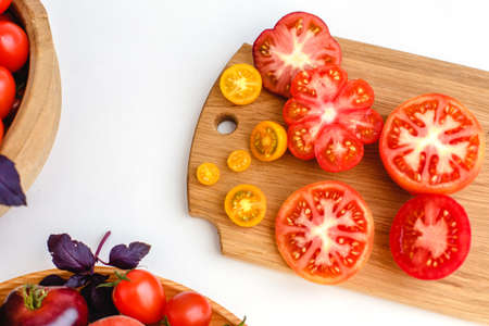 Different tomatoes on white. Vegetables of different varieties