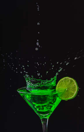 Green drink in a glass. Green water or limnad. A splash of green liquid similar to absinthe. Alcohol and alcoholism.の写真素材