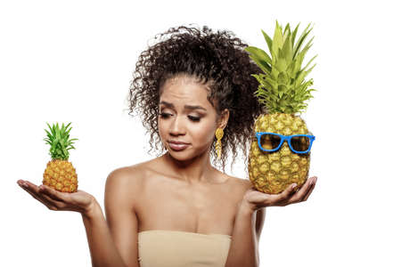 Model with pineapple in hands. African American Girl with Exotic Fruit. Cheerful woman with a smile relaxing on vacation. Image about summer time, smile and restの写真素材