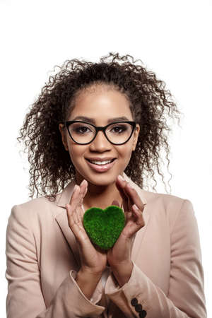 Model girl with a green heart in her hands. Woman with a symbol of care for nature, ecology and the environment.の写真素材