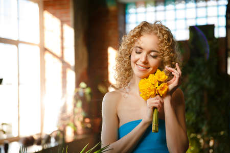 happy beauty. Woman with yellow flowers in interiors. spring girl. Joyful holiday of spring. Model celebrate mother's day, women's day or birthday.の写真素材