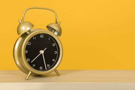Retro clock standing on 7.30 in the morning on a yellow backgroundの写真素材