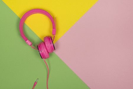 Pink headphone on a multi colored background with copy spaceの写真素材