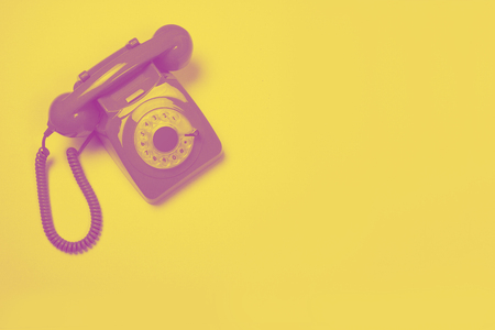 Pink retro telephone on a yellow background in a duo tone design with space for copyの写真素材