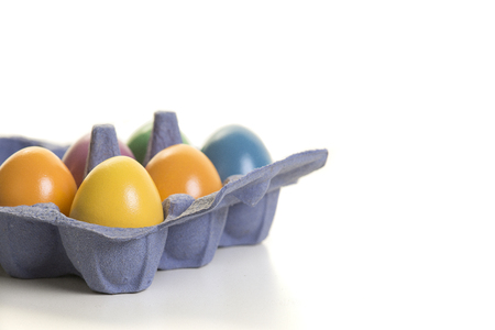 Colorful eggs in a egg carton on a white background with space for copyの写真素材