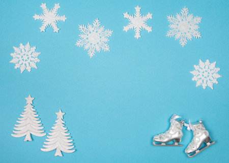 Winter flatlay with snowflakes and christmas tree ornaments on a blue background with space for copyの写真素材