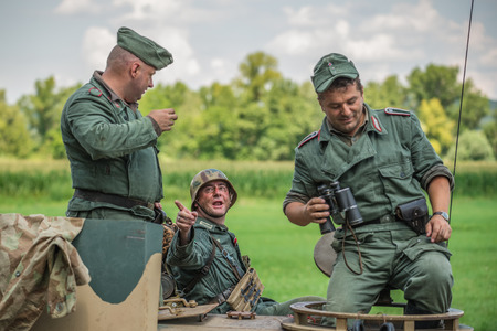 STARY TEKOV, SLOVAKIA - JULY 26,2014: German soldier talking to comrades on a tank during reenactment of World War II fightのeditorial素材