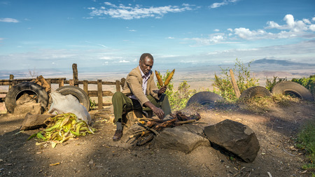 NAROK COUNTY, KENYA - OCTOBER 16, 2014 : African man in a suit sells corn  at the Kamandura Mai-Mahiu Narok Road near the Great Rift Valley in Kenya, Africa.のeditorial素材