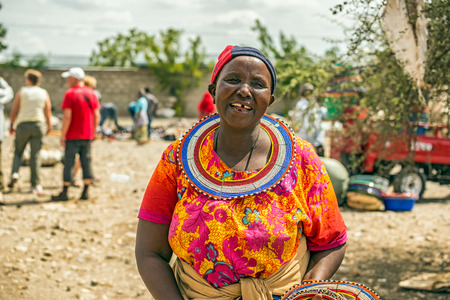 MTO WA MBU, ARUSHA, TANZANIA - OCTOBER 22, 2014 : Traditionally dressed african woman from the masai tribe selling merchandise
 in the Masai Central Market of Mto Wa Mbu.のeditorial素材
