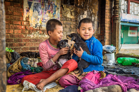 KATHMANDU, NEPAL - OCTOBER 22, 2015 : Homeless children playing with puppies in the street of Kathmandu. At least two million Nepalis remained homeless after the major earthquake on 25 April 2015.のeditorial素材