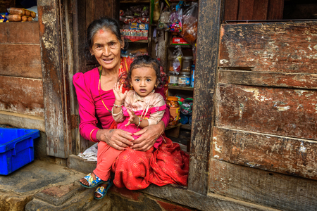KATHMANDU, NEPAL - OCTOBER 19, 2015 : Old nepalese lady with a child sells goods in her store.のeditorial素材