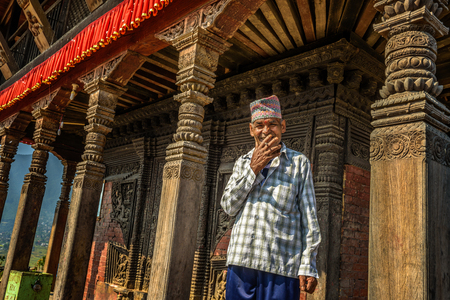 KATHMANDU, NEPAL - OCTOBER 20, 2015 : Old buddhist monk smoking cigarette in his temple in Kathmanduのeditorial素材
