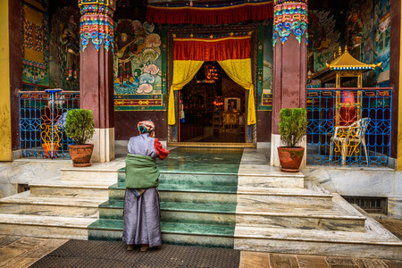 KATHMANDU, NEPAL - OCTOBER 28, 2015 : Old woman wearing traditional costume prays in front of a buddhist temple in Kathmandu, Nepalの写真素材