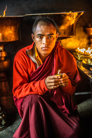 KATHMANDU, NEPAL - OCTOBER 28, 2015 : Buddhist monk lighting up candlelight inside a buddhist temple in Kathmandu.のeditorial素材