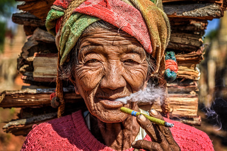 IN DEIN, MYANMAR - JANUARY 27, 2016 : old wrinkled woman smokes  a cheroot cigarのeditorial素材