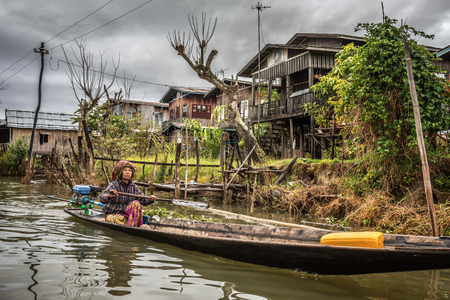 INLE LAKE, MYANMAR - JANUARY 26, 2016 :  Woman of the Inthar tribe  boating through her village.  Inthar people build wooden houses on piles to live on the lake.のeditorial素材
