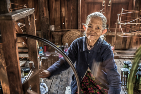 INLE LAKE, MYANMAR - JANUARY 26, 2016 :  Woman worker weaves fabric in a weaving factory on Inle Lake.のeditorial素材