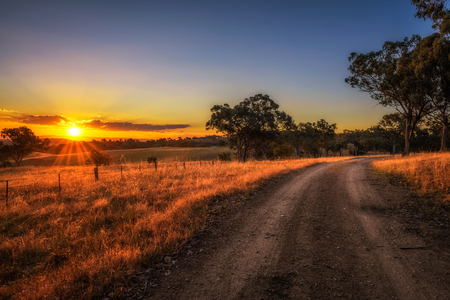 Scenic countryside landscape with rural dirt road at sunset in Australiaの写真素材