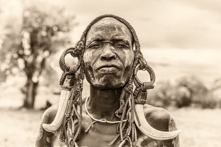 OMO VALLEY, ETHIOPIA - MAY 7, 2015 : Warrior from the african tribe Mursi with traditional horns in Mago National Park, Ethiopia.  Vintage black and white processed.のeditorial素材