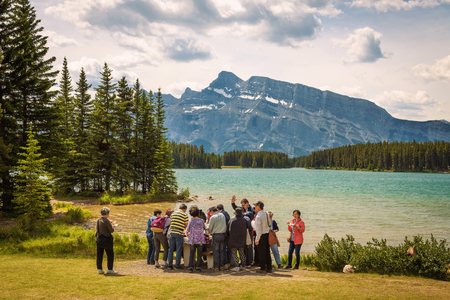 TWO JACK LAKE, ALBERTA, CANADA - JUNE 26, 2017 : Group of Asian tourists having lunch at the two jack lake in Banff National Park with Mt. Rundle in the background.のeditorial素材