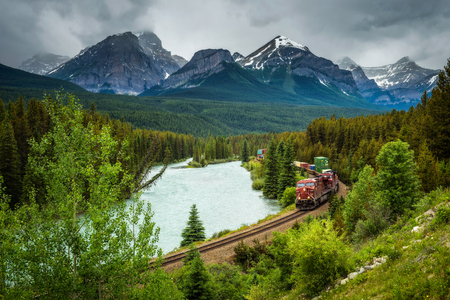 Train passing through the Morant's Curve in bow valley with Rocky Mountains in the background, Banff National Park, Alberta Canadaのeditorial素材