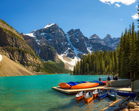 Canoes on a jetty at  Moraine lake in Banff National Park, Alberta, Canada, with snow-covered peaks of canadian Rocky Mountains in the background.のeditorial素材