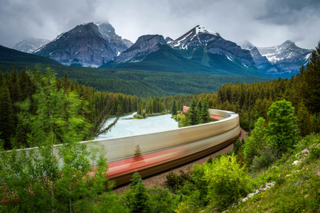 Train passing through the Morant's Curve in bow valley with Rocky Mountains in the background, Banff National Park, Alberta Canada. Long exposure.の写真素材
