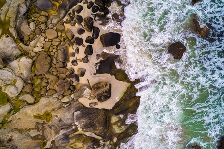 Aerial view looking down at sea waves hitting rocksの写真素材