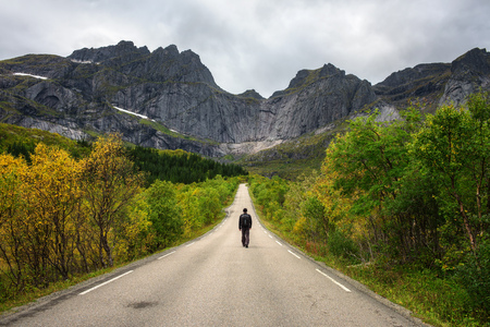 Hiker walks on a scenic road on Lofoten islands in Norwayの写真素材