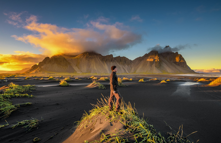 Hiker enjoying sunset at Vestrahorn and its black sand beach in Icelandの写真素材