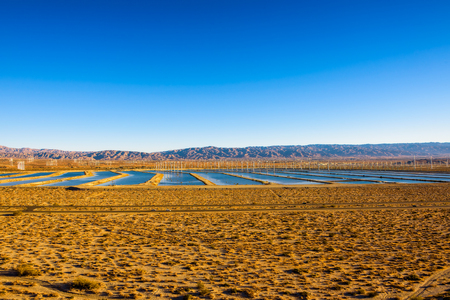 Windmills farm and water reservoirs along a highway in Mojave desertの写真素材
