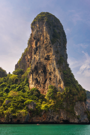 Small boat under huge cliff of Phi Phi islandsの写真素材