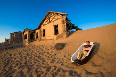 Tourist sits in a bathtub in Kolmanskop ghost town, Namibiaのeditorial素材