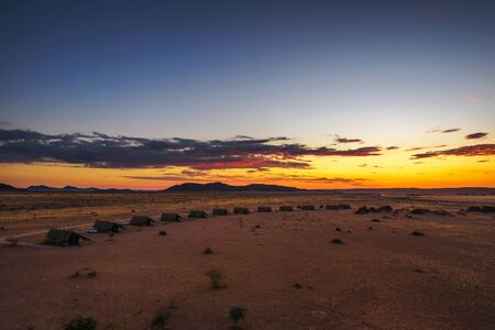 Sunset above small chalets of a desert lodge near Sossusvlei in Namibiaの写真素材