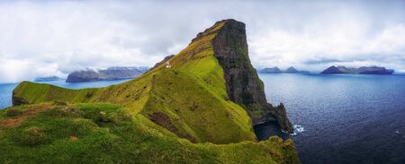 Small lighthouse located near huge cliffs on island of Kalsoy, Faroe Islandsの写真素材