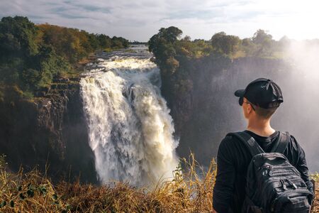 Tourist looks at the Victoria Falls on Zambezi River in Zimbabweの写真素材