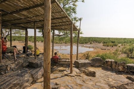 Tourists wait for wildlife at the Moringa waterhole near Halali, Etosha, Namibiaのeditorial素材