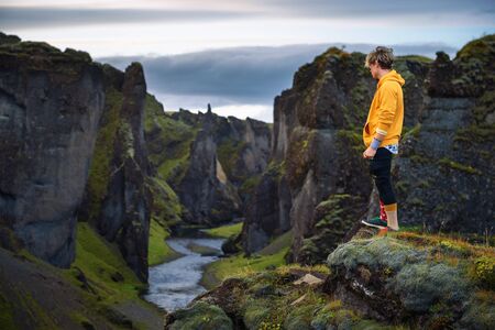 Young hiker standing at the edge of the Fjadrargljufur Canyon in Icelandの写真素材