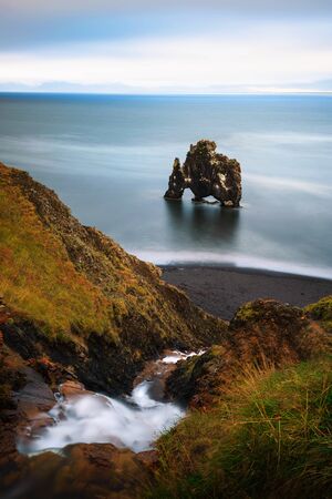 Hvitserkur basalt stack and a small waterfall in northern Icelandの写真素材