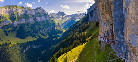 Aerial panorama of the Swiss Alps and a historic mountain restaurant under the Ascher cliff located in the Appenzell region in Switzerlandの写真素材