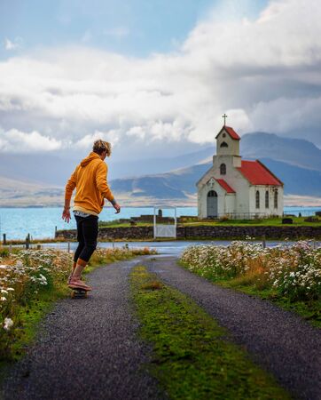 Young skater skateboarding towards a church and a cemetery in Icelandの写真素材