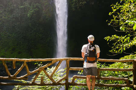 Tourist looking at the La Fortuna Waterfall in Costa Rica. The waterfall is located on the Arenal River at the base of the dormant Chato volcano.の写真素材