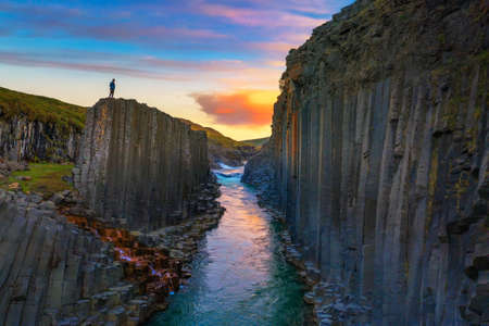 Hiker standing at the top of Studlagil Canyon in Iceland at sunsetの写真素材