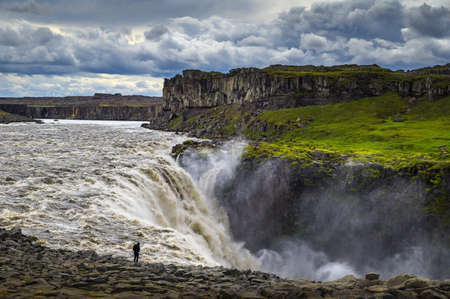 Hiker standing close to the Dettifoss waterfall in Icelandの写真素材
