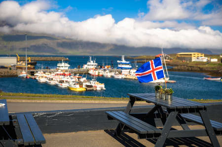 Flag of Iceland placed on a restaurant table with a harbor in the backgroundの写真素材