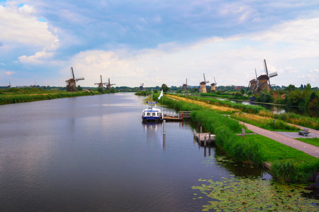 Historic windmills and a river with a boat in Kinderdijk, Netherlandsの写真素材