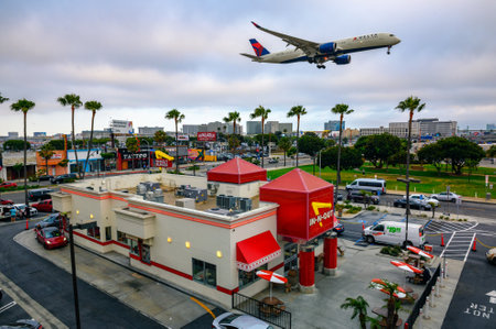 Delta Airlines plane flies above In-N-Out Burger restaurant while landing at the Los Angeles International Airport LAXのeditorial素材
