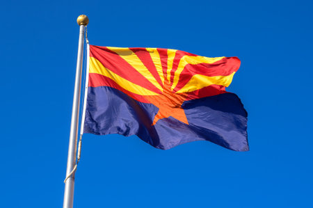 Arizona state flag waving in the wind against a cloudless blue sky
