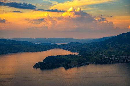 A scenic view of Lake Lucerne from Burgenstock mountain, Switzerland, at sunset. Vibrant skies and lush greenery enhance the serene landscape.の写真素材