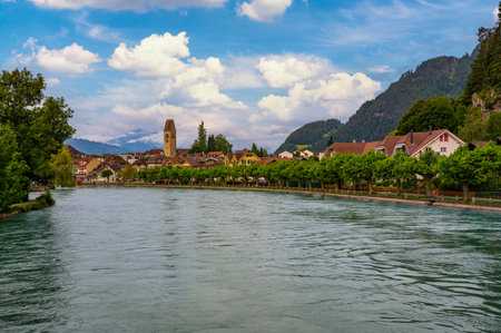 Scenic view of Interlaken, Switzerland, with the Aare River and surrounding Swiss Alps in the background, featuring traditional buildings and lush greenery.の写真素材